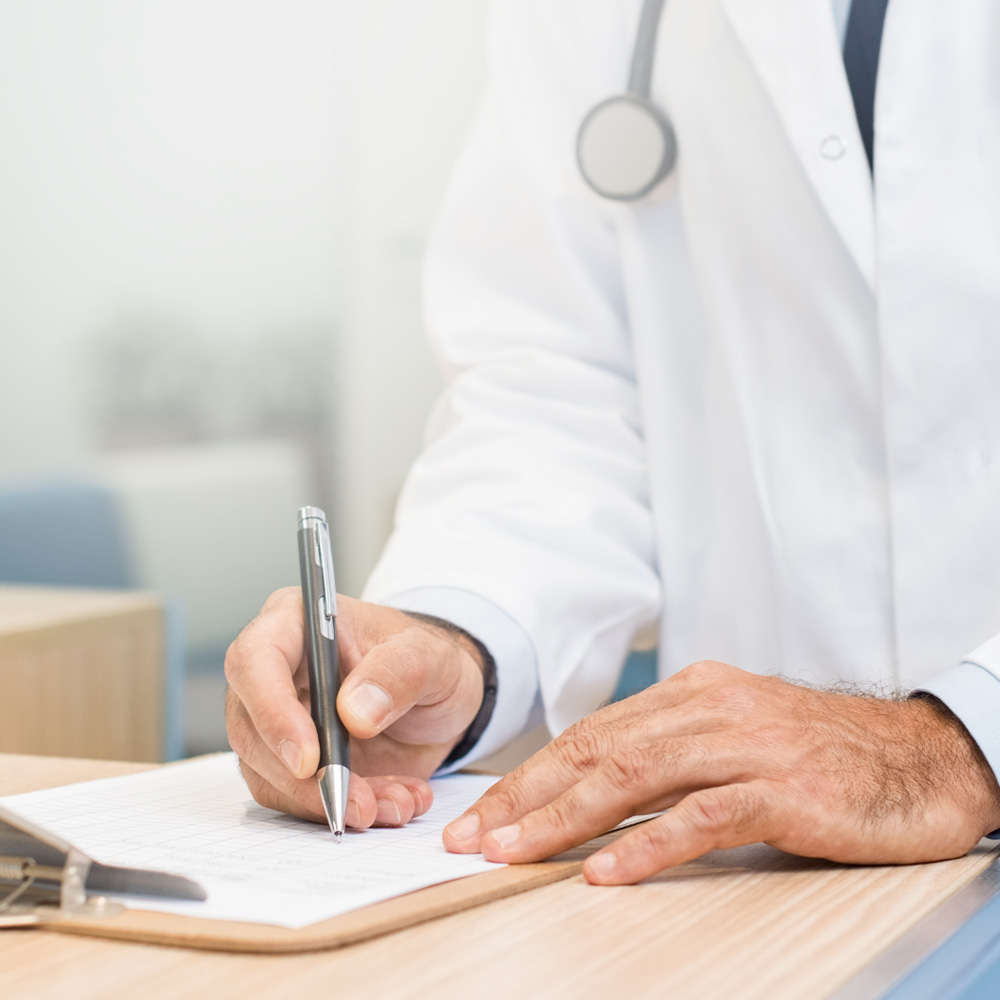 Médico com jaleco branco preenchendo uma ficha sobre a mesa, destacando um momento de consulta ou análise clínica.